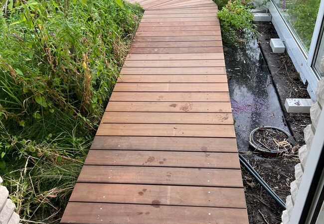 Holzweg mit Holzplatten im Wintergarten über Teich