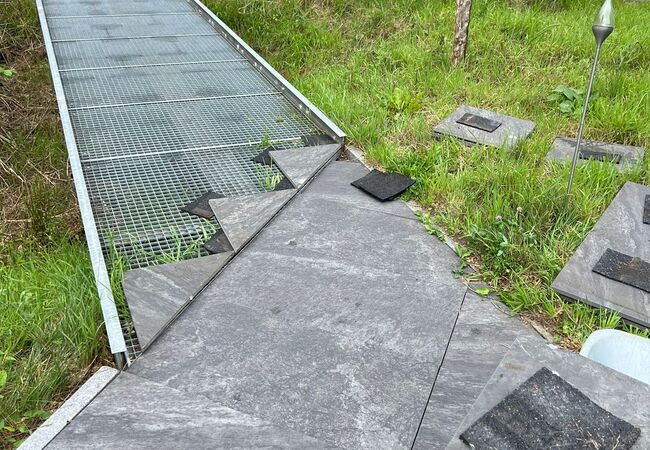 Verlelgung von Natursteinplatten auf dem Weg, teils fertig, teils unfertig mit Gitternetz für Verlegung