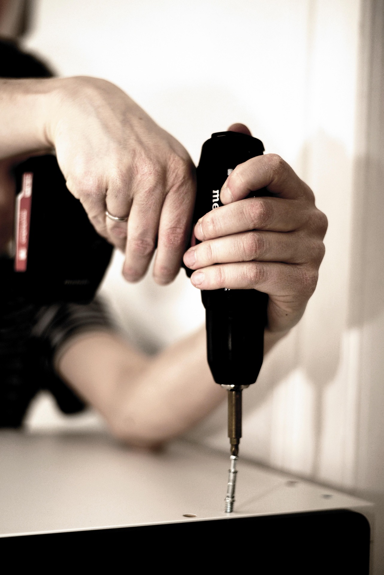 handwerker mit Akkuschrauber in der Hand bohrt gerade eine Platte fest